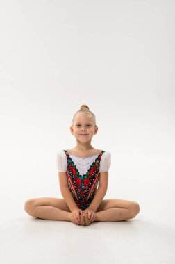 Koklear implantı olan genç bir jimnastikçi kız kelebek pozisyonunda oturuyor. Sakinlik, iyileşme ve çocukluk jimnastiğinin ve işitme yenilenmesinin kapsayıcı ruhu