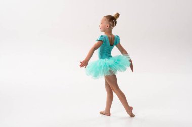 Koklear implantı olan küçük bir balerin turkuaz etekle dans ediyor. İşitme teknolojisinin ahengi, çocukluk zarafeti ve müzik ve hareket yoluyla dahil edilme.