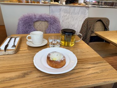 Sıcak bir sabah molası sırasında çay ve hamur işleriyle dolu bir kafe masası. Sıcaklık, konfor ve günlük neşe rahat yaşam tarzı anlarında