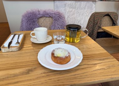 Sıcak bir kafe masasında sabah çayı ve hamur işi servis ediliyor. Kentsel yaşam tarzı ve basit zevklerde rahatlama, sıcaklık ve denge