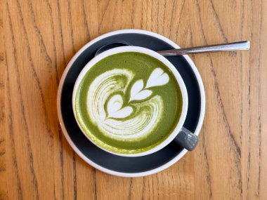 Yukarıdan izlenmiş kalp desenli bir Matcha latte. Minimalizm, sakin enerji ve Japonlardan esinlenilmiş kafe ritüeli