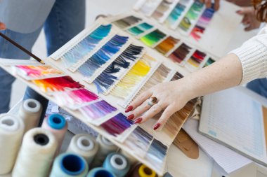 Yaratıcı çalışma alanında tekstil renk tonlarını seçen eller. Modern moda tasarımında işbirliği, estetik karar ve takım çalışması