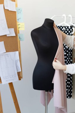 Yaratıcı atölyede manken üzerine hafif kumaş örten tasarımcı. Moda işçiliği ve giyim tasarımında stil, süreç ve ilham