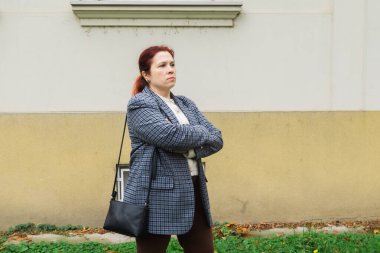 Bina duvarının yanında kolları çapraz duran üzgün kadın. Özgüven, düşünce ve içsel güç..