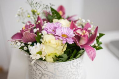 Gül ve orkide ile karışık çiçeklerin yakın çekimi. Ev dekorunda yumuşak dokular, ahenk ve doğal zarafet..