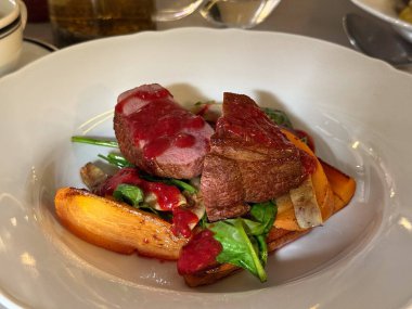 Kırmızı soslu kızarmış et ve yakın plan sebzeler. Gurme sunumu, karşıtlık ve rafine yemek atmosferi yaratıcılık ve lezzeti ifade ediyor