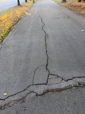 Görünür hasar çizgileriyle asfalt yüzeyi çatlamış. Kentsel bozulma, altyapı aşınması ve zaman geçişi.