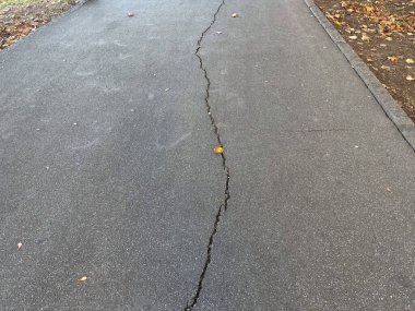 Görünür hasar çizgileriyle asfalt yüzeyi çatlamış. Kentsel bozulma, altyapı aşınması ve zaman geçişi.