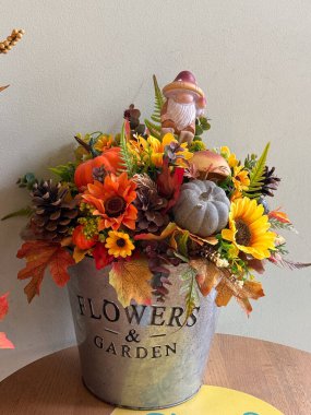 Gnome ve balkabaklarıyla metal kapta sonbahar çiçeği aranjmanı. Mevsimlik ev dekorasyonu, rahat atmosfer ve kırsal hasat ilhamı.