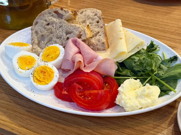 Yumurta, ekmek, jambon, peynir ve sebzeli sağlıklı bir kahvaltı. Dengeli sabah beslenmesi, taze malzemeler ve ev yapımı yemek ilhamı.