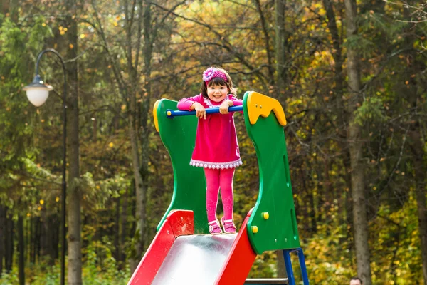 Niña jugando en el patio de recreo en otoño — Foto de Stock