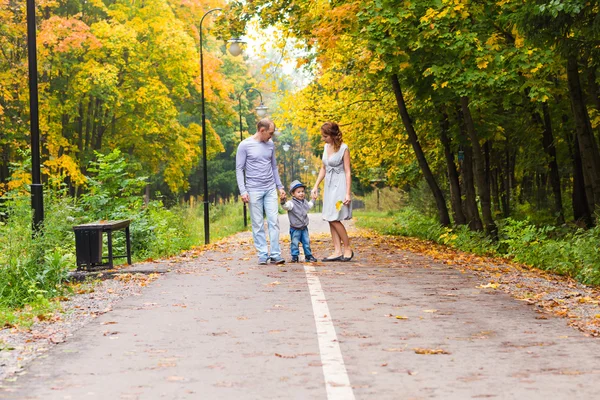 Família jovem para um passeio no parque de outono com bebê — Fotografia de Stock