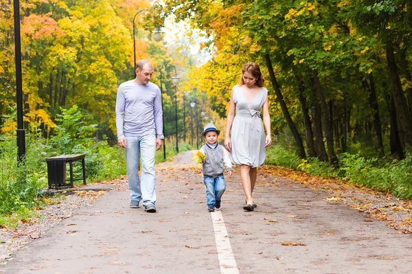 Familia joven para dar un paseo en el parque de otoño con el bebé — Foto de Stock