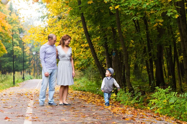 Ung familj för en promenad i parken hösten med baby — Stockfoto