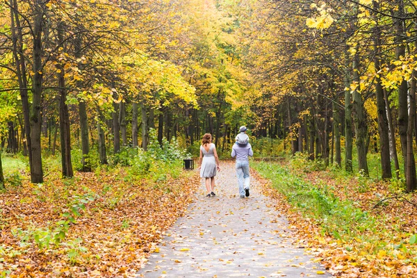 Família jovem para um passeio no parque de outono com bebê — Fotografia de Stock
