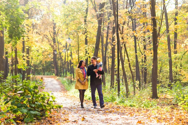Ung familj för en promenad i parken hösten med baby — Stockfoto