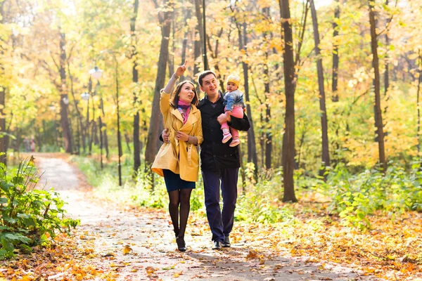 赤ちゃんと一緒に秋の公園で散歩に若い家族 — ストック写真