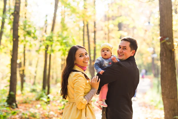 Família jovem para um passeio no parque de outono com bebê — Fotografia de Stock