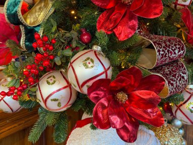 Yılbaşı süsleri ve her zaman yeşil olan dallarda sergilenen kırmızı çiçekler. Mevsimlik ruh hali ve kutlama için dekoratif zarafet.
