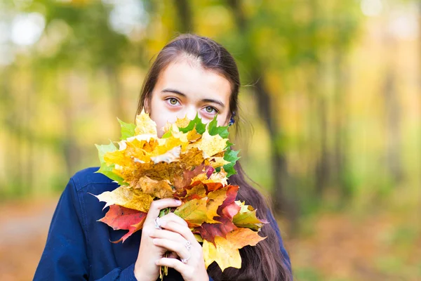 Ragazza che copre il viso con una foglia d'autunno — Foto Stock