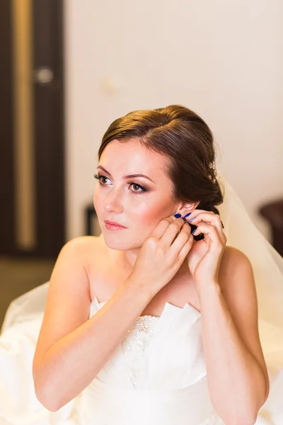 Hermosa novia joven con maquillaje de boda y peinado, mujer recién casada preparación final para la boda. Feliz novio de la novia esperando. Momento del día de boda . — Foto de Stock