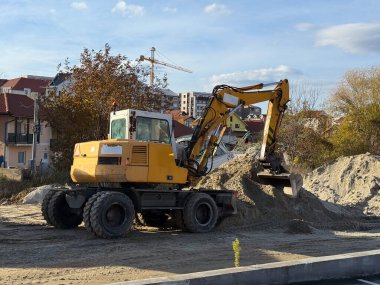 Sarı kazıcı toprağı hareket ettiriyor. Ağır makineler, inşaat işleri ve kentsel çevrede endüstriyel ilerleme