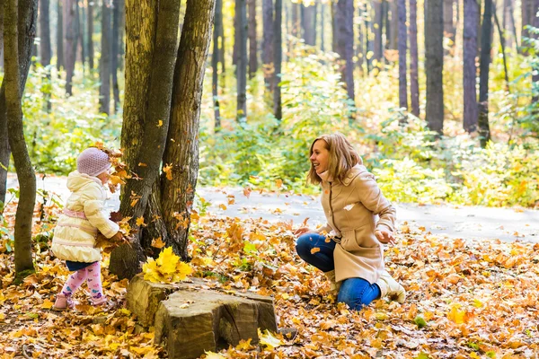 Feliz familia madre e hija pequeña jugando en otoño a pie —  Fotos de Stock