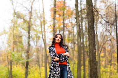 Sonbahar parkında duran genç güzel ciddi kadın portresi.