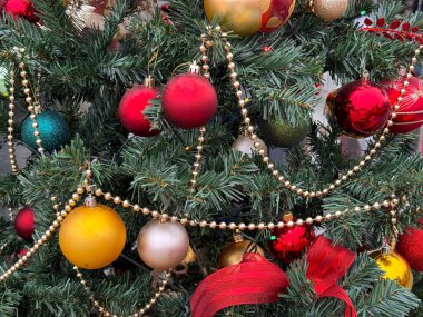 Süslü köknar ağacındaki Noel süsleri ve çelenklerin detaylı görünümü. Tatil dekorasyonu, kış kutlaması, şenlikli atmosfer ve geleneksel mevsimlik stil.