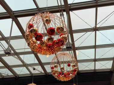 Cam tavanın altında süs eşyalarıyla noel süsleri asmak. Şenlikli iç dekorasyon, mevsimlik aydınlanma, tatil atmosferi ve modern alışveriş merkezi tasarımı.