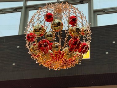 Aydınlatılmış noel süs küresi içeride asılı duruyor. Tatil dekorasyonu, mevsimsel ışıklandırma tasarımı, şenlikli iç tasarım ve kış kutlaması.