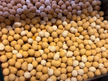 Küçük yuvarlak bezelye atıştırmalıkları bir kabı sıcak nötr tonlarla dolduruyor. Basit malzemeler, günlük atıştırma, ve bitki bazlı gıda kültürü tekerrür ve düzenli doku ile ifade edilir.