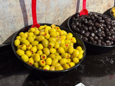 Biberli yeşil zeytinler büfe tezgahında sergileniyor. Akdeniz malzeme seçimi, aperatif servisi, yiyecek bolluğu ve günlük yemek atmosferi.