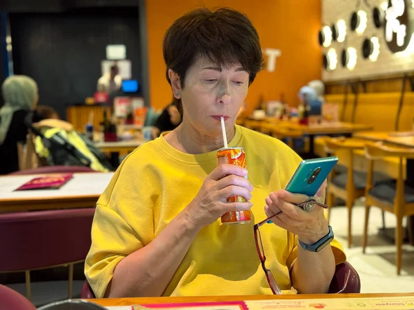 Kafede cep telefonu kullanan bir kadın. Odaklanmış ilgi, modern yaşam tarzı, gündelik yemek deneyimi, sosyal etkileşim