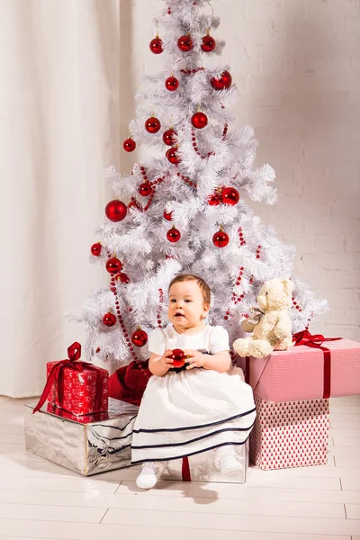 Χαριτωμένο κοριτσάκι που κάθεται κάτω από το χριστουγεννιάτικο δέντρο — Φωτογραφία Αρχείου