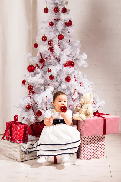 Χαριτωμένο κοριτσάκι που κάθεται κάτω από το χριστουγεννιάτικο δέντρο — Φωτογραφία Αρχείου