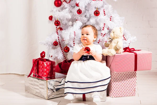 Menina bonito sentado sob a árvore de Natal — Fotografia de Stock