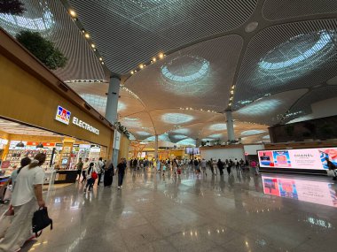 İSTANBUL, TURKEY - 3 Ağustos 2025: Kalabalık modern İstanbul havalimanı, Türkiye terminali ve alışveriş alanından geçen yolcular. Seyahat akışı, ulaşım merkezi, uluslararası hareket ve çağdaş kamusal alan mimarisi