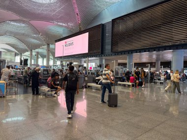 İstanbul havaalanı içindeki güvenlik tarama alanında yolcu ve bagaj var. Seyahat güvenlik prosedürleri, uluslararası havacılık kontrolü, ulaşım düzenlemesi, organize hareket ve modern havaalanı güvenliği ortamı