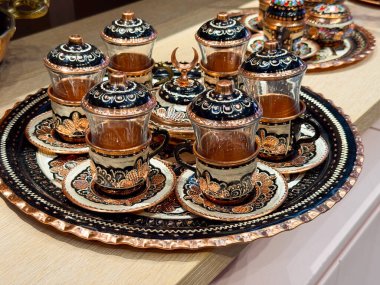 Cam bardaklar ve metal tepsilerle süslü Türk çayı seti. Çay kültürü ritüeli, geleneksel konukseverlik, dekoratif metalcilik, kültürel sembolizm, törensel sofra takımı ve zanaatkarlık..