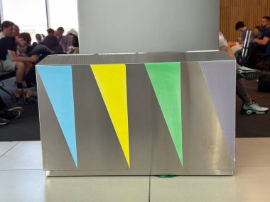 Kamusal iç alana yerleştirilmiş renk kodlu panellerle atık ayıklama kabı. Geri dönüşüm sistemi, çevre sorumluluğu, sürdürülebilir altyapı, şehir temizliği, modern atık yönetimi çözümü.