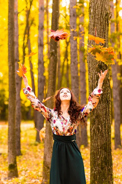 Jeune belle femme jetant des feuilles jaunes dans l'air — Photo