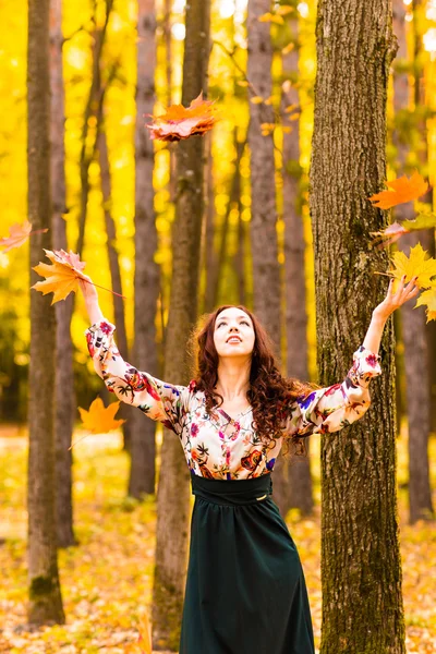 Jeune belle femme jetant des feuilles jaunes dans l'air — Photo