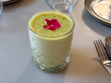 Çiçek garnitürlü köpüklü yeşil içeceğin üst görüntüsü. Minimalizm, tazelik ve yaratıcı gıda tasarımı