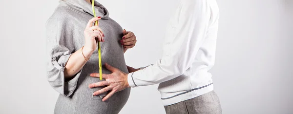 白い背景の上の妊婦の腹に触れる男性の手. — ストック写真