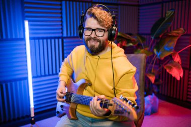 Müzik stüdyosunda elektro gitar çalan sakallı adam. Müzik sektöründe performans ve gösteri, müzik yayını ve kaydı