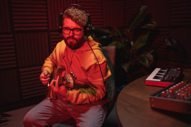 Gitarlı bir kayıt stüdyosunda şarkı söyleyen erkek vokalist. Erkek şarkıcı bir şarkı söylüyor ve gitar çalıyor. Ses kaydı ve müzik akışı kavramı