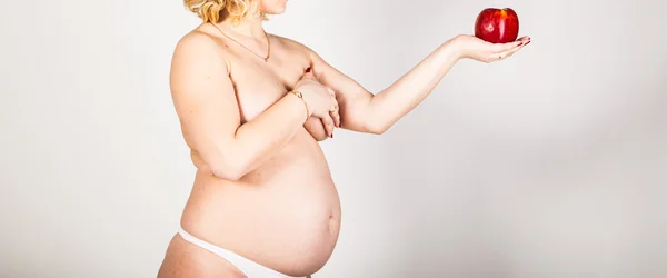 Mujer embarazada sosteniendo manzana roja — Foto de Stock