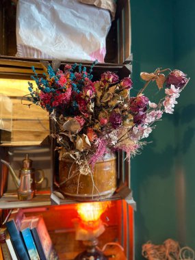 İçerideki ahşap rafta duran kurumuş çiçek buketi. Klasik dekor tasarımı, nostaljik atmosfer, botanik doku ve rahat iç hayat kompozisyonu.