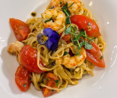 Beyaz tabakta servis edilen karides ve domatesli makarna. Mutfak sunumu, gurme yemeği, dengeli beslenme, deniz ürünleri mutfağı ve rafine gıda hazırlama yoluyla duyusal keyif..